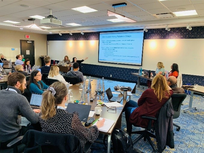 Workshop facilitator presenting a slide to participants seated with laptops in a breakout room